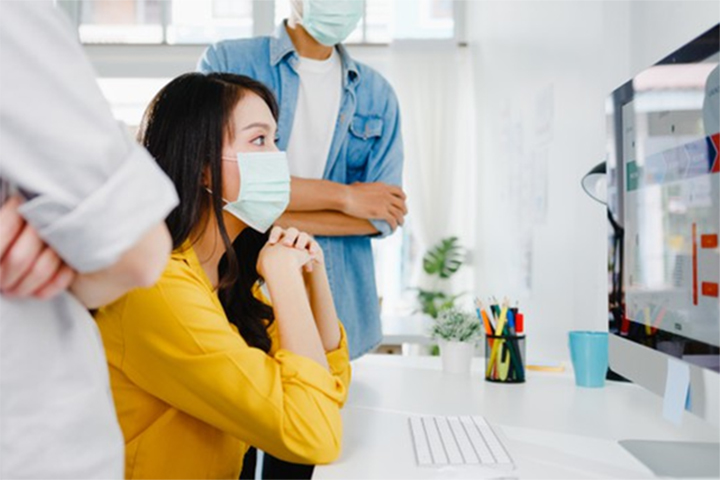 Mulher com seus colegas de trabalho em frente ao computador analisando tendências para o ITSM