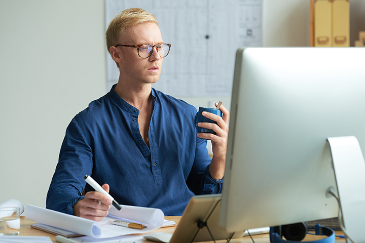 Product Owner homem acessando computador e fazendo anotações