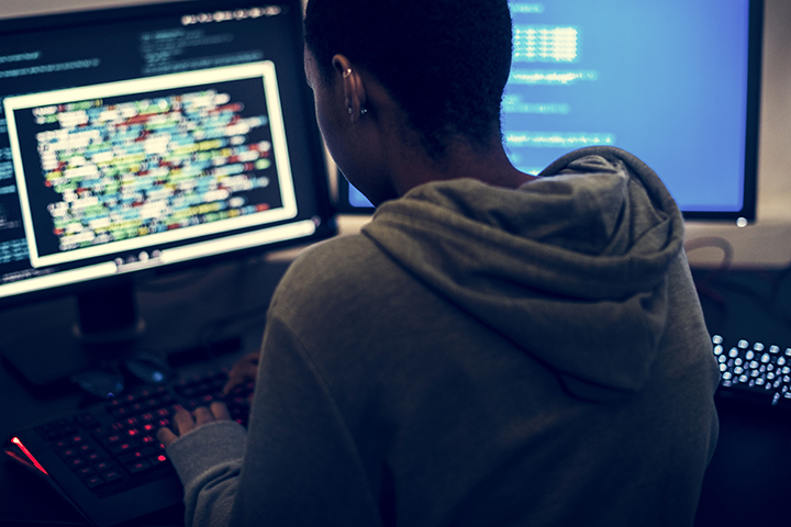 Homem hacker usando computador para invadir outros sistemas conforme CSFR