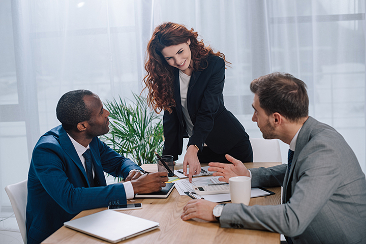 Mulher conversando com dois colegas de trabalho sobre a prática do Lean IT