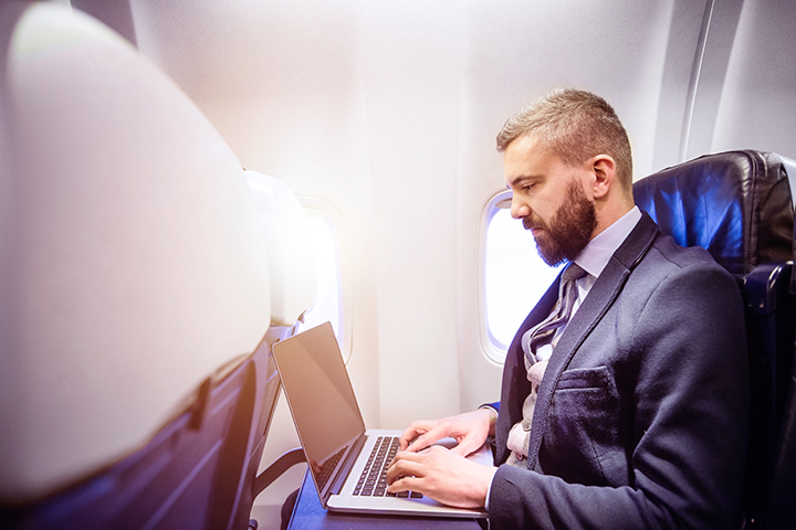 Homem usando laptop dentro do avião durante o vôo com segurança da informação
