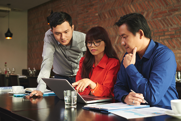 Homens e mulher acessando laptop com e utilizando o CobiT 5
