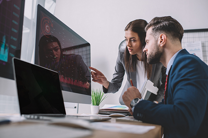 Analistas de segurança da informação usando gráficos em monitores de computador enquanto trabalhava
