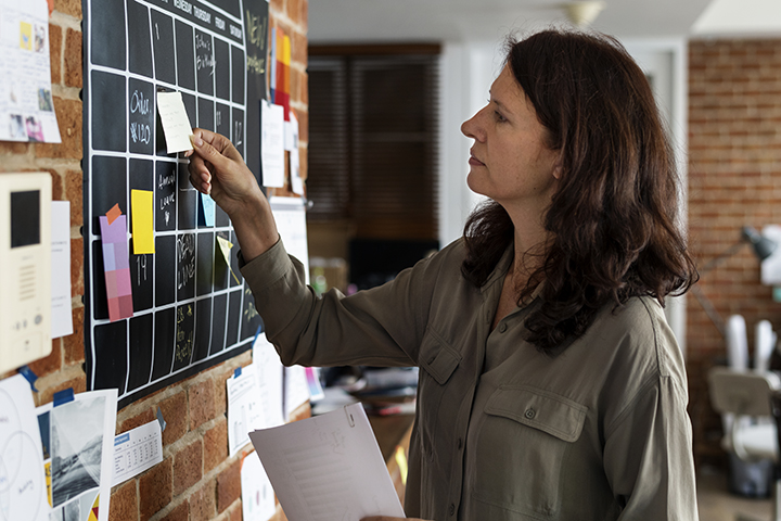 Mulher usando post it em quadro para facilitar trabalho de modo framework