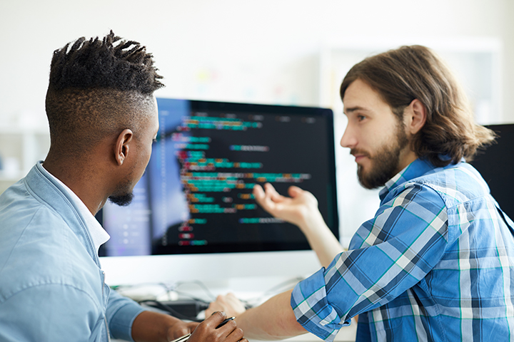 Dois homens jovens usando o COBOL para programar aplicativos